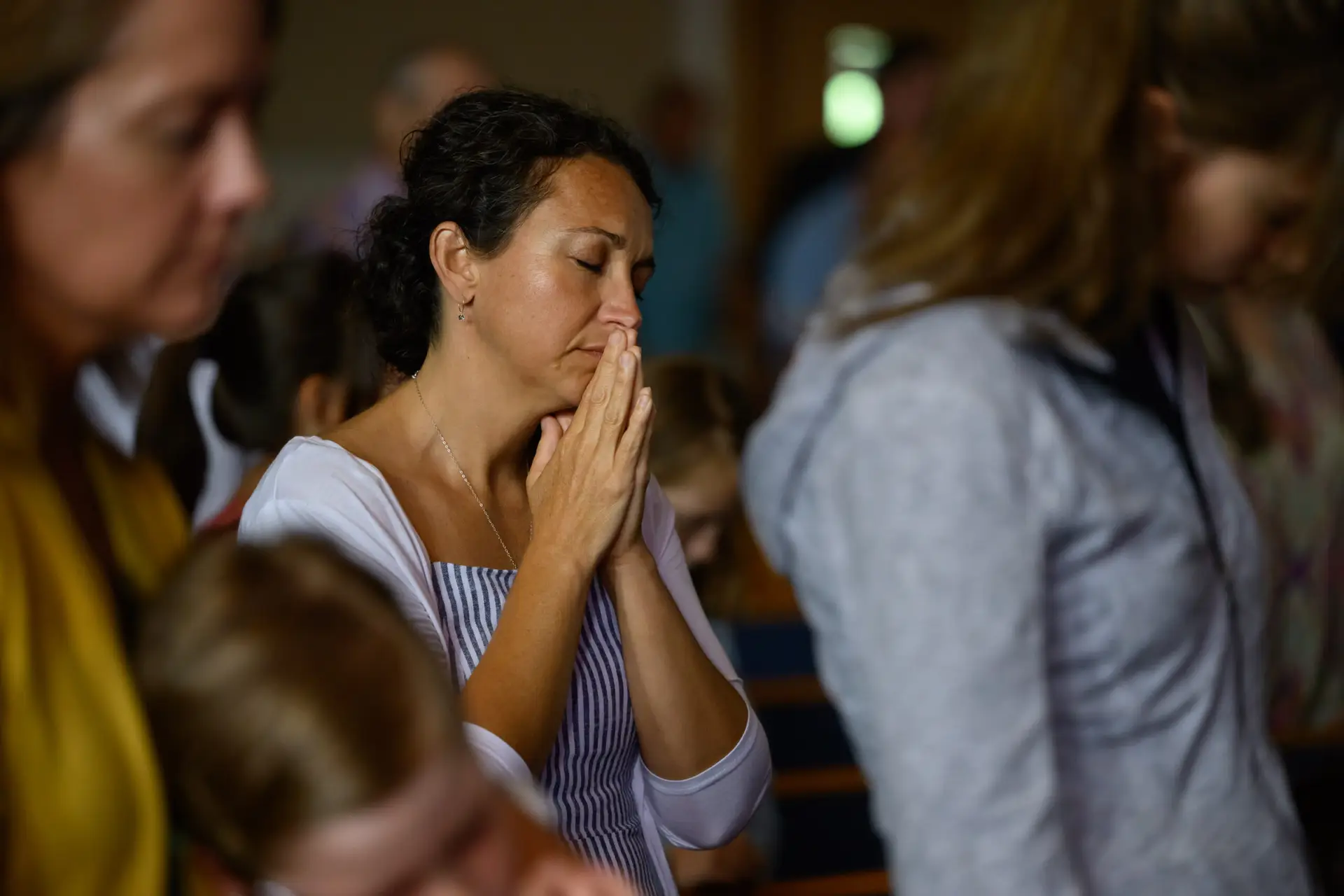 Southmont congregation worshipping together, hands raised, with the stained-glass cross behind the stage